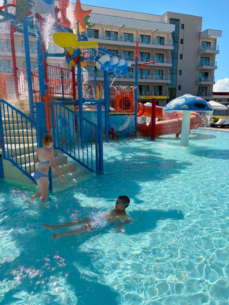 A smiling little boy splashing in the shallow children's pool at DIT Evrika Waterpark.